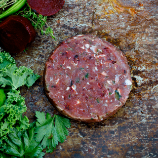 Disk of raw Wild Kangaroo & Beetroot blend dog food on bench with beetroot andgreens.